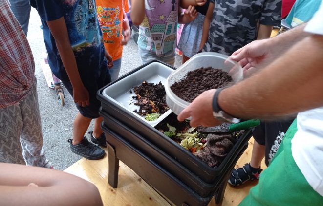 Fotografia de la darrera Festa de la Ciència, amb públic de diferents edats observant diferents estats de descomposició de restes orgàniques i una vermicompostadora.
