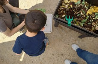 Imatge d'una criatura d'esquenes durant l'activitat amb una vermicompostadora.