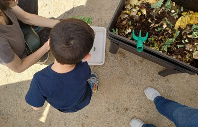Imatge d'una criatura d'esquenes durant l'activitat amb una vermicompostadora.